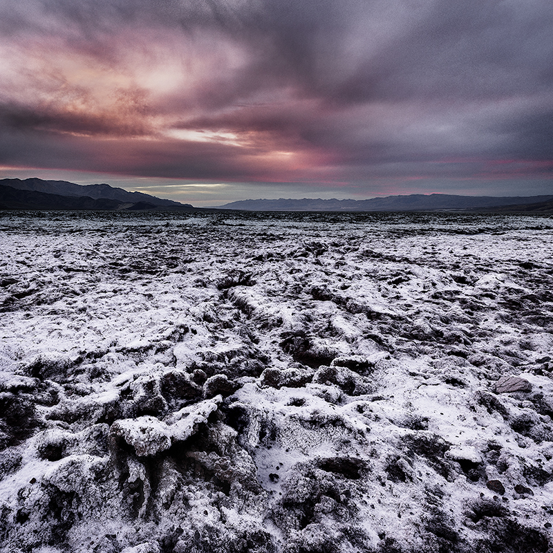 Death Valley playa with dark sunset sky and gnarly salt formations