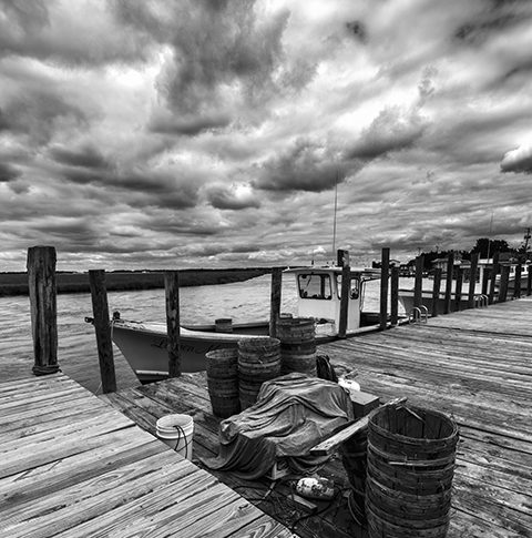 Smyrna working dock with dramatic sky fishing boat and crabbing equipment in black and white